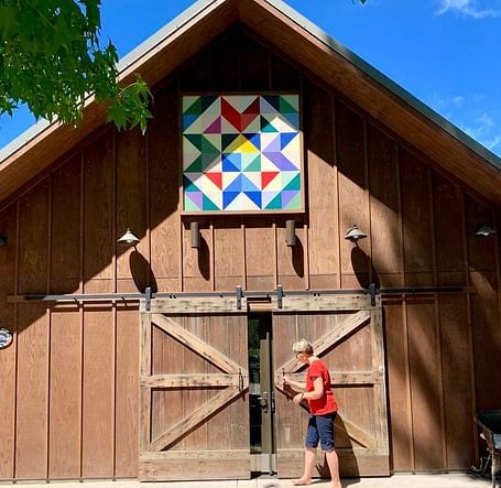 A person stands near the partially open double doors of a building with a geometric design above.