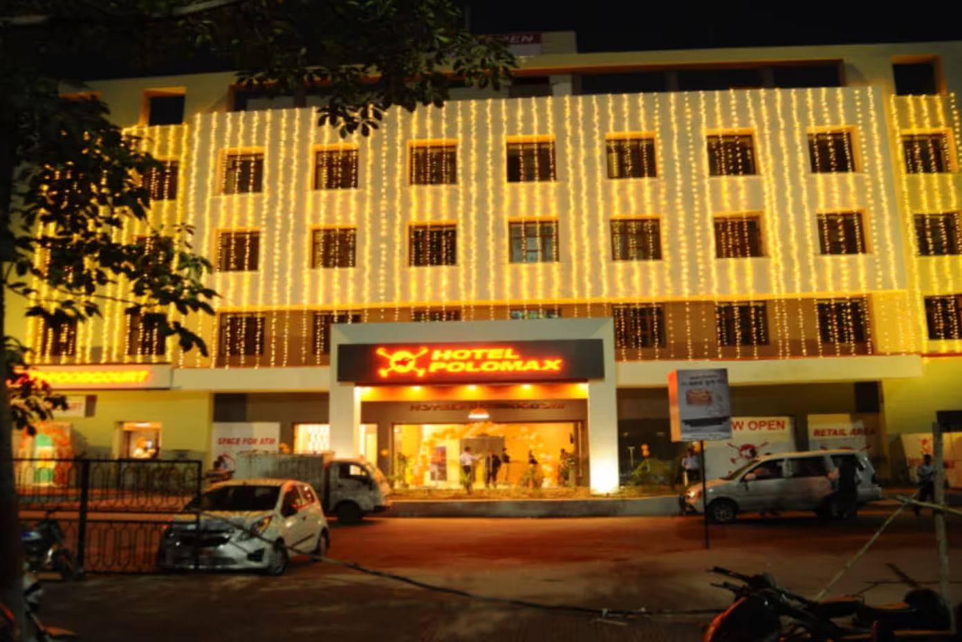 Facade shot of Max Hotel Prayagraj building illuminated at night, with a grand entrance and warm lighting.