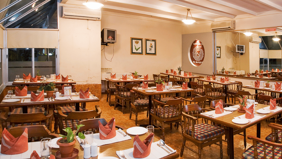 An overview of Kamat's Veg Restaurant, the best veg restaurant in Silvassa, with modern ambience and four chair seating, an AC and a large mirror inside at VITS Kamats Resort, Silvassa.