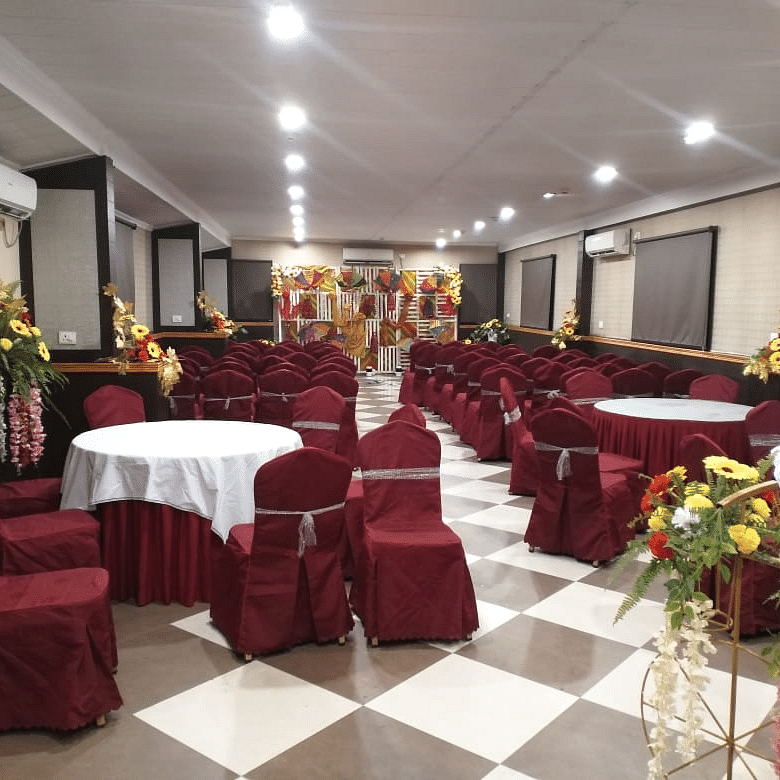 Spacious banquet hall with maroon seating, round tables, and floral centrepieces at Central Courtyard Boutique Hotel.