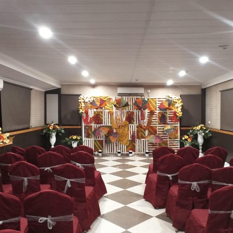  Banquet hall setup with maroon chairs and a well-lit stage for special events at Central Courtyard Boutique Hotel.