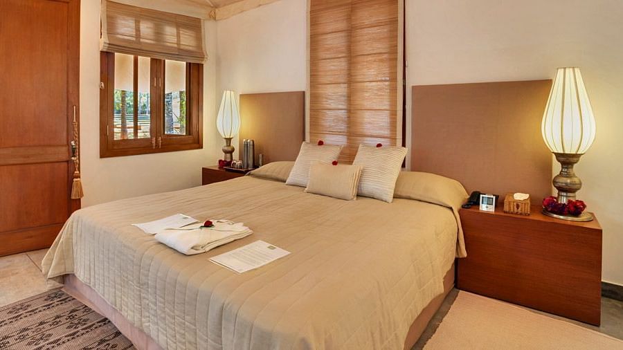 A bedroom with a bed, lamps, and a view of a garden - Shreyas Retreat