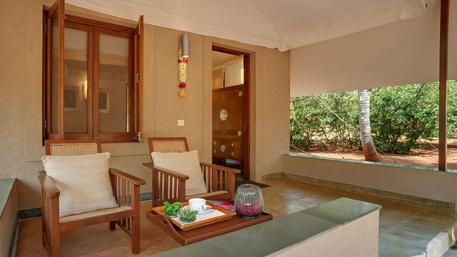 A living room with a couch, chairs, and a view of a garden - Shreyas Retreat