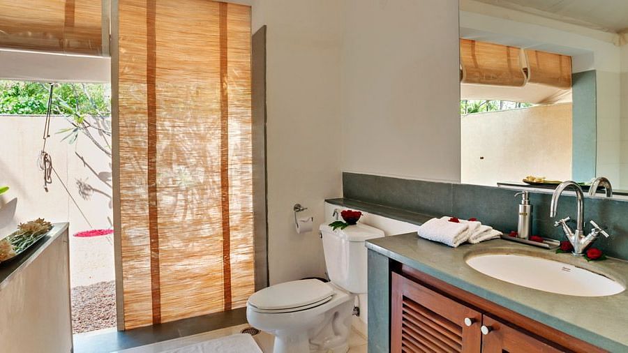 A bathroom with a sink and mirror, sliding glass doors leading to a patio, natural light - Shreyas Retreat