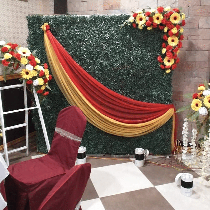 Elegant photo booth setup with green foliage, red drapes, and floral arrangements at Central Courtyard Boutique Hotel.