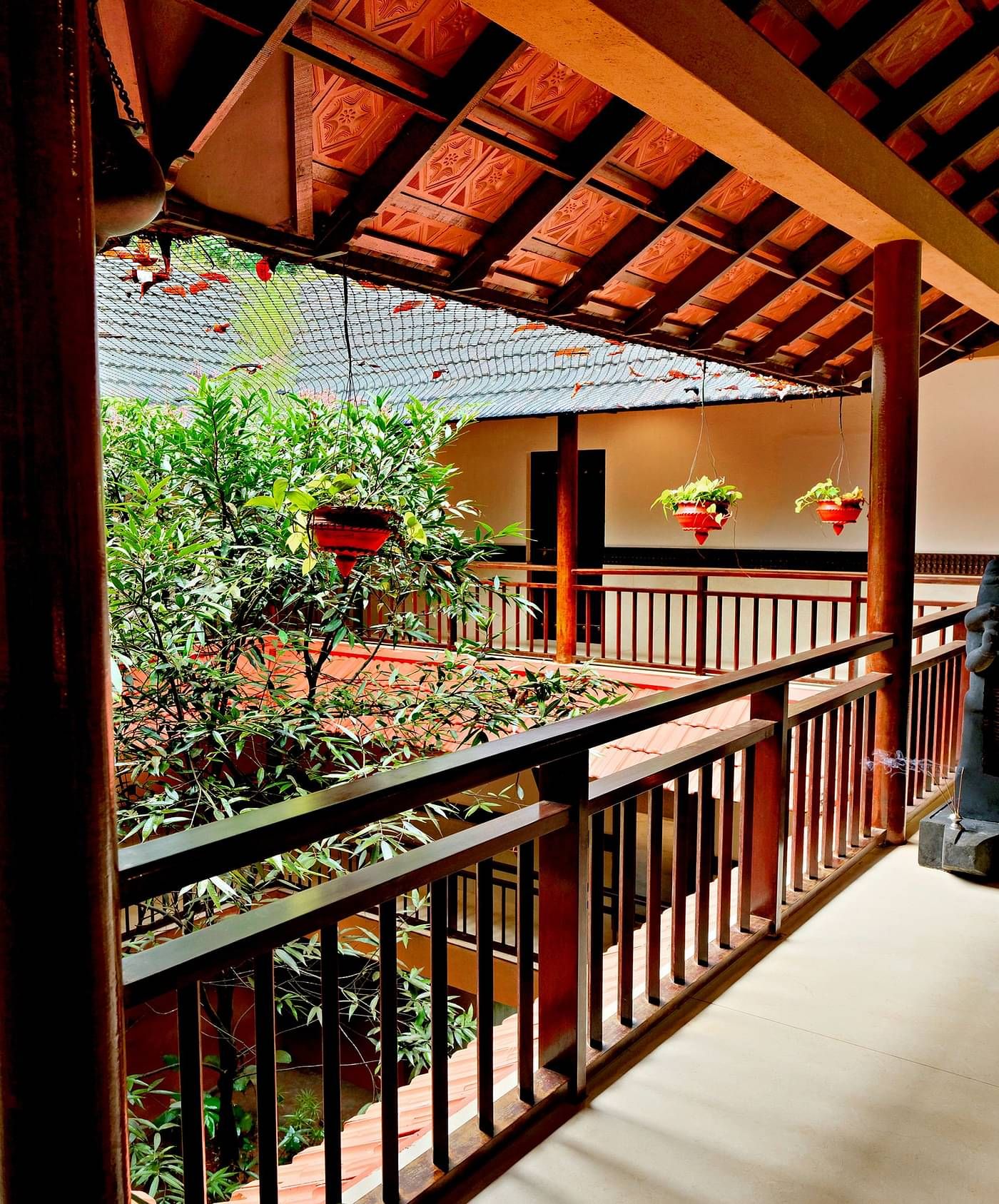 Outdoor corridor with wooden railings and greenery view at Vythiri Resort, Wayanad