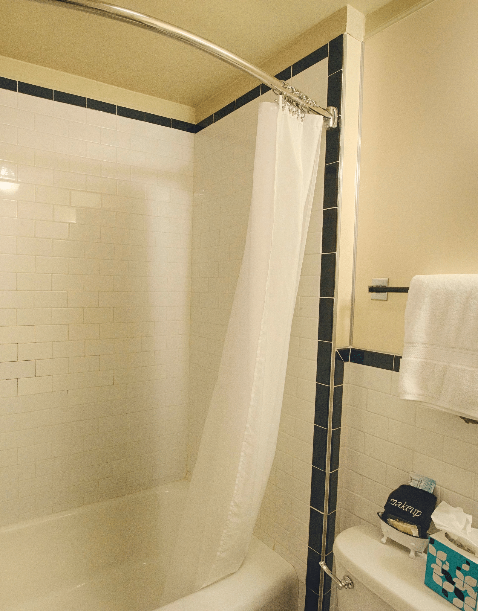 a bathtub with the shower curtains tucked inside the tub with a commode besides it - Historic Tapoco Lodge