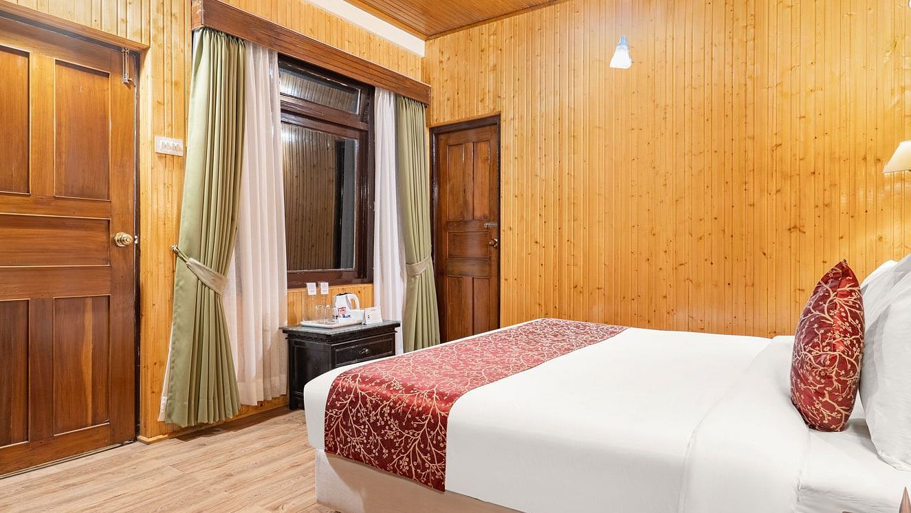 Side view of a room with bed and wooden wall panelling at Summit Tashi Ghang Heritage Resort, Pelling