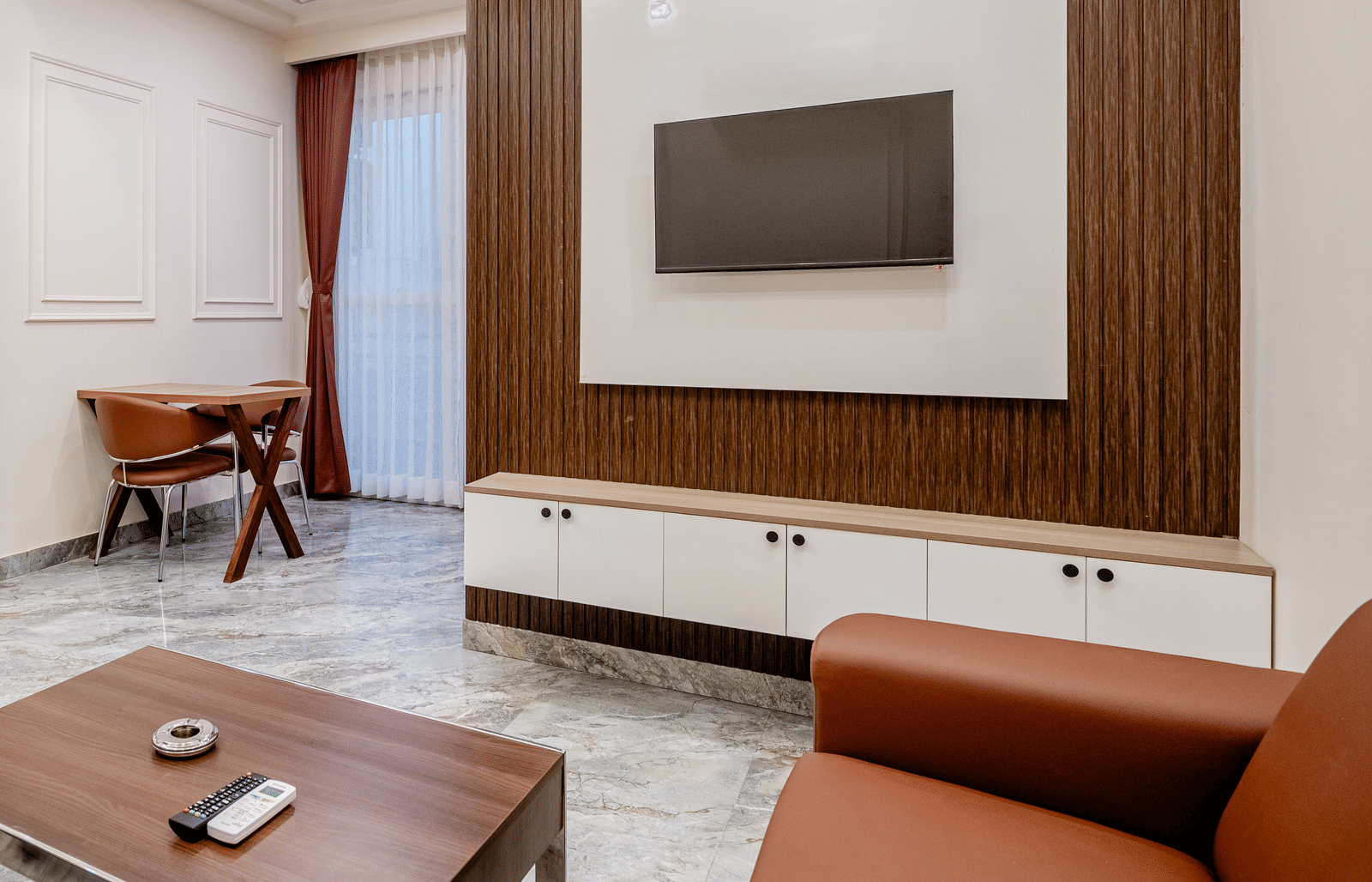 Spacious living area with sofa set, table, and wall-mounted TV at Lime Tree 1BHK Service Apartment Near Artemis Hospital Gurgaon.