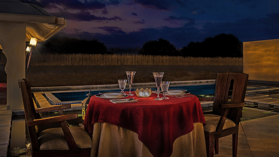 Romantic outdoor poolside dining with red table setting at Evolve Back Hampi