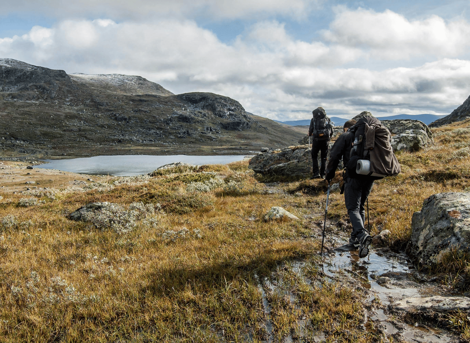 A group of people walking along a mountain trail with backpacks.
