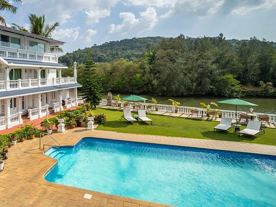 The facade of the hotel alongside the pool - Stone Wood Riverfront Resort, Siolim