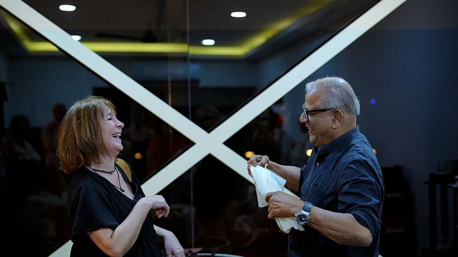A man with glasses holds up a piece of paper, gesturing towards a laughing woman in a room .