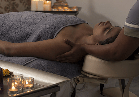 Person receiving a massage on a table, close-up shot, spa treatment - Shreyas Retreat