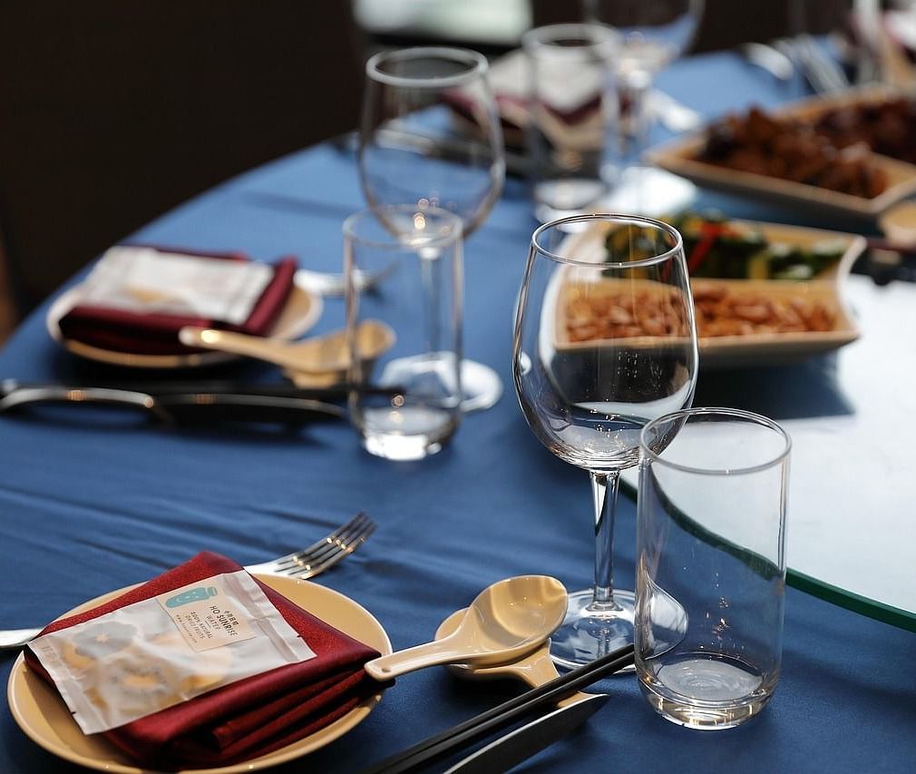 A close up shot of a round dining table with sparkly glassware and cutlery arranged on it.