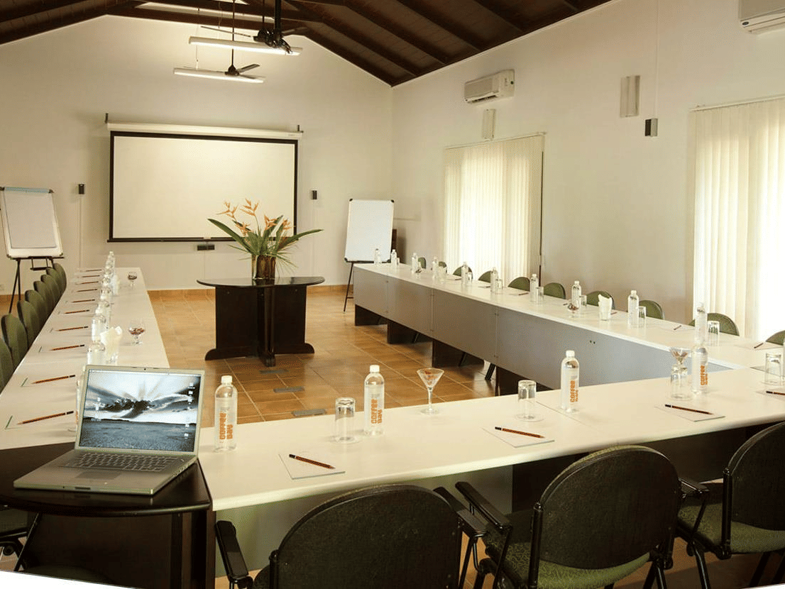Conference Hall in Bandipur at The serai Bandipur with a U-shaped table and a projector screen under warm lighting
