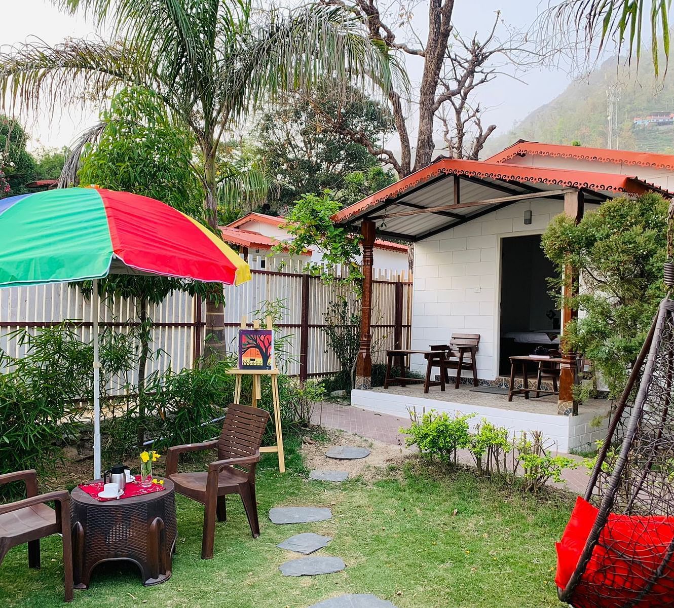 a garden behind one of the rooms with seats under a canopy in the garden - Neer Ganga Resorts