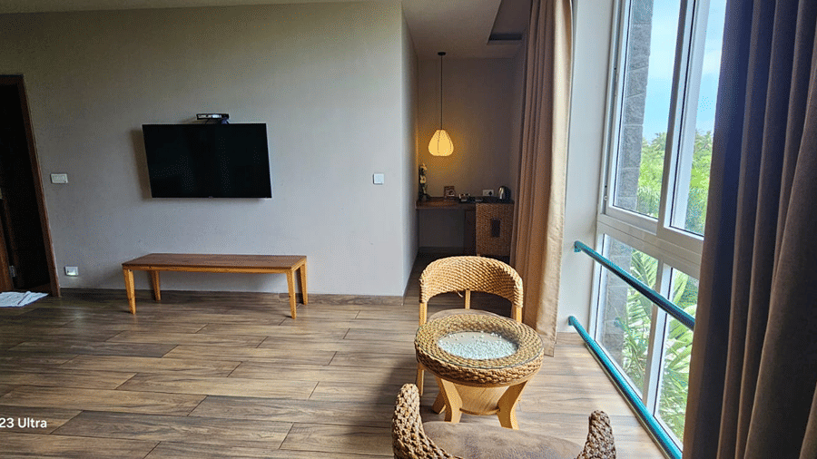 Wooden chair beside large windows with curtains at Cholaa Dynasty, Kumbakonam.