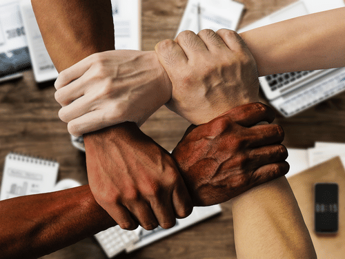 four people joining their hands to promote team work