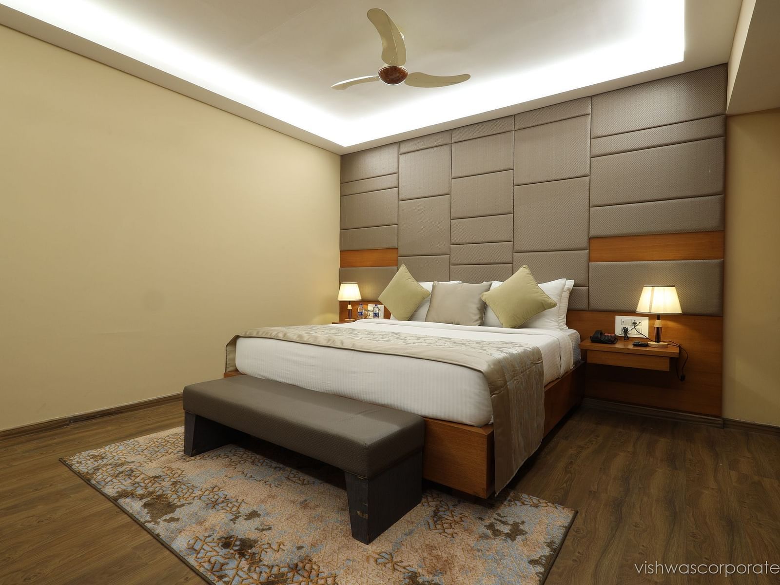 Hotel room interior with a bed, a bench, and a fan, a guest accommodation at Rang Lords Inn Bharuch