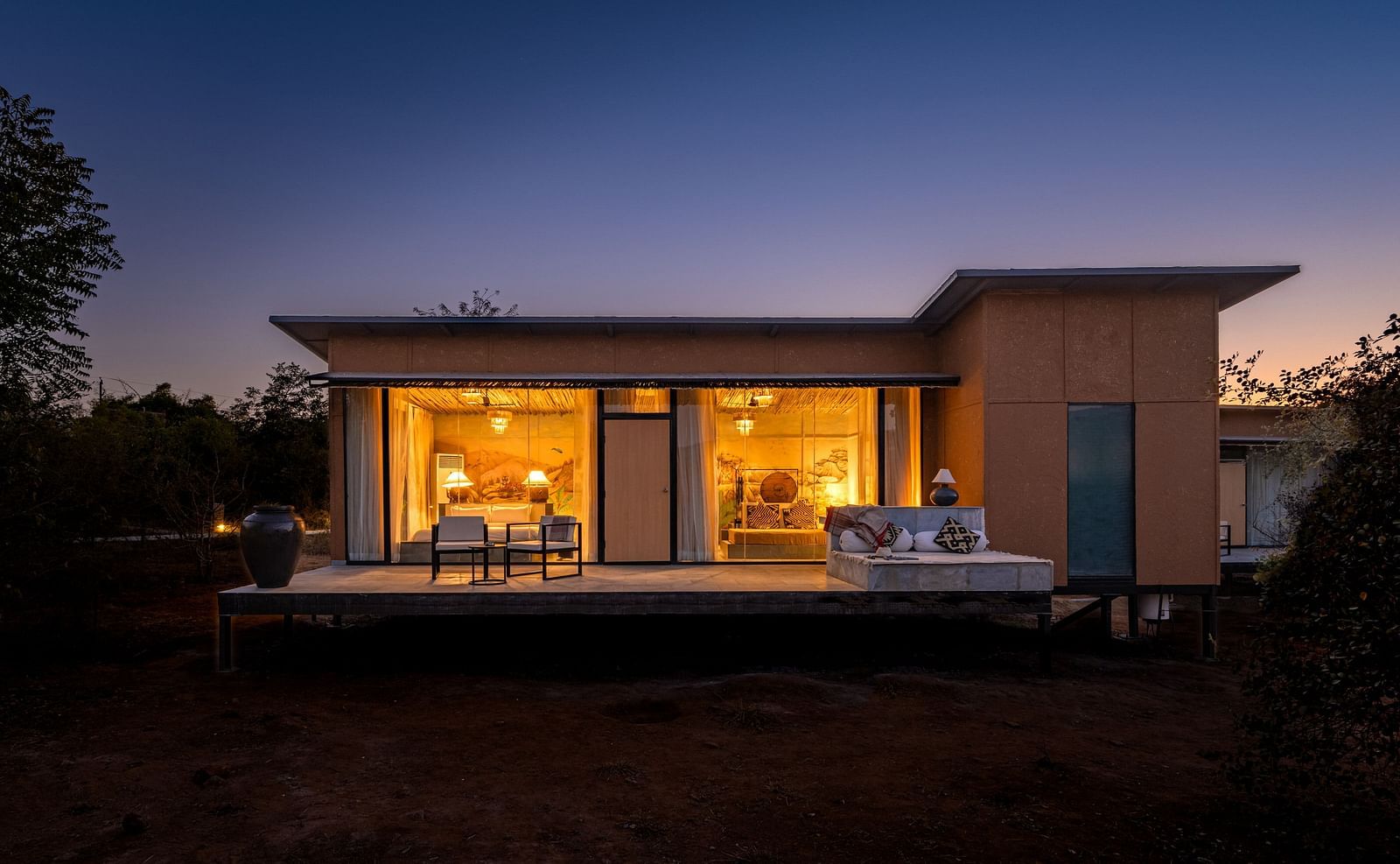 A facade image of a room with bright lighting and greenery around - Utsav Camp Sariska.