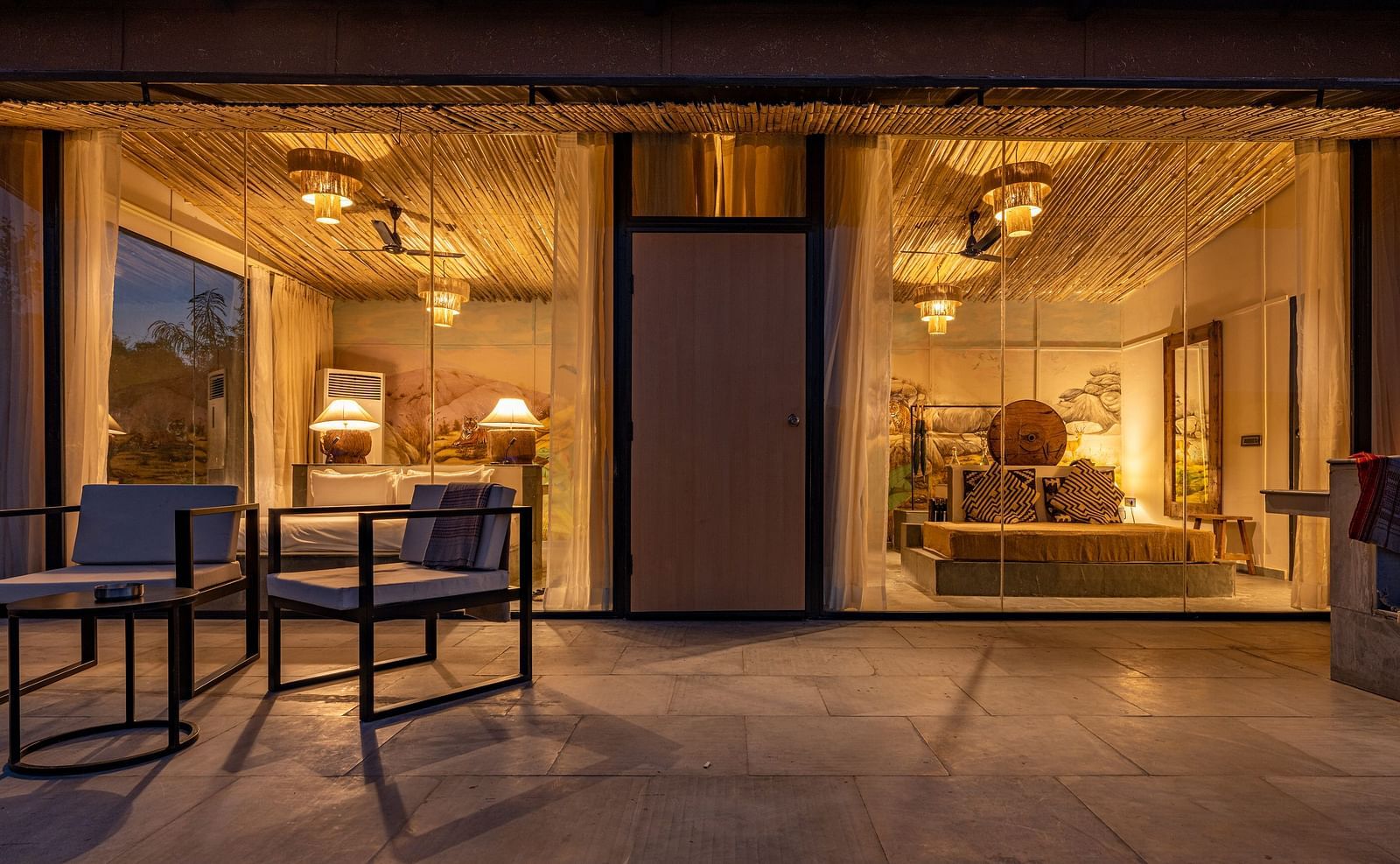 A facade image of a room with bright decorative lighting with outdoor seating arrangement - Utsav Camp Sariska