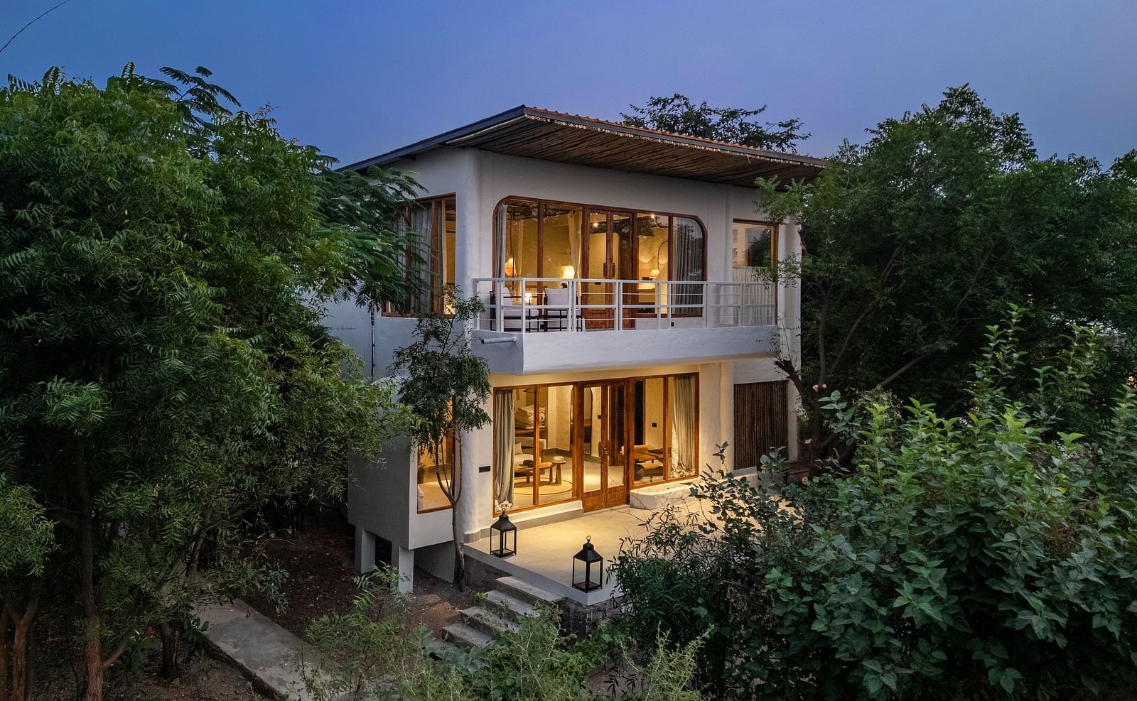 Exterior of a Forest villa surrounded by plants and trees in daylight.