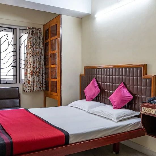 Side view of Double room with plush bed, side table and large window - Hotel Ram International,  Pondicherry