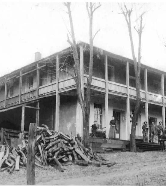 A black and white image of a building with trees surrounding it being logged - The Groveland Hotel.
