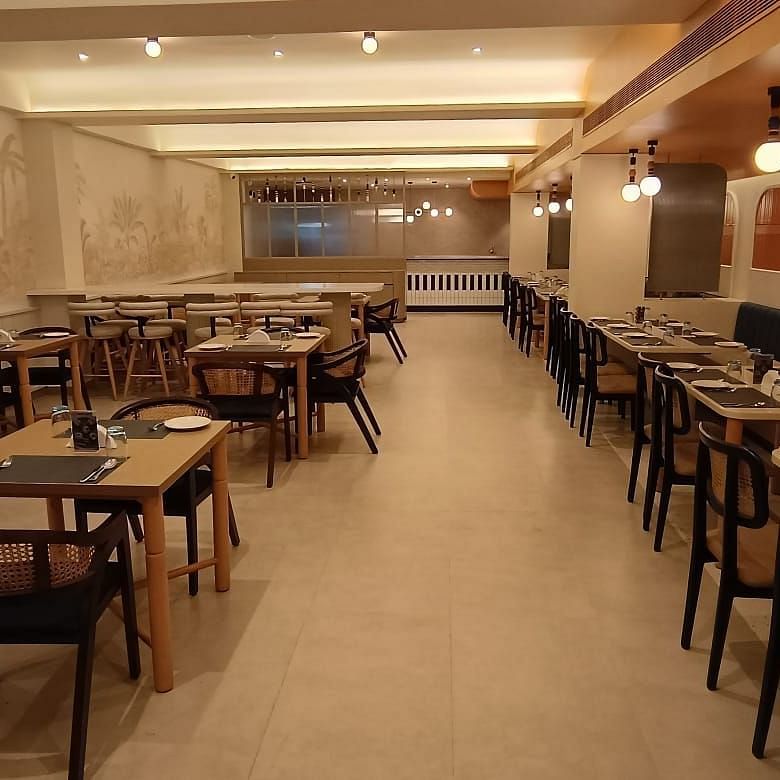 An extended view of the interior of Hotel Manorath showcasing neatly organised dining tables, cutlery and warm lighting at Lords Eco Inn in Belagavi.