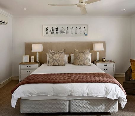 A double bed with a ceiling fan hanging over it in a bedroom.