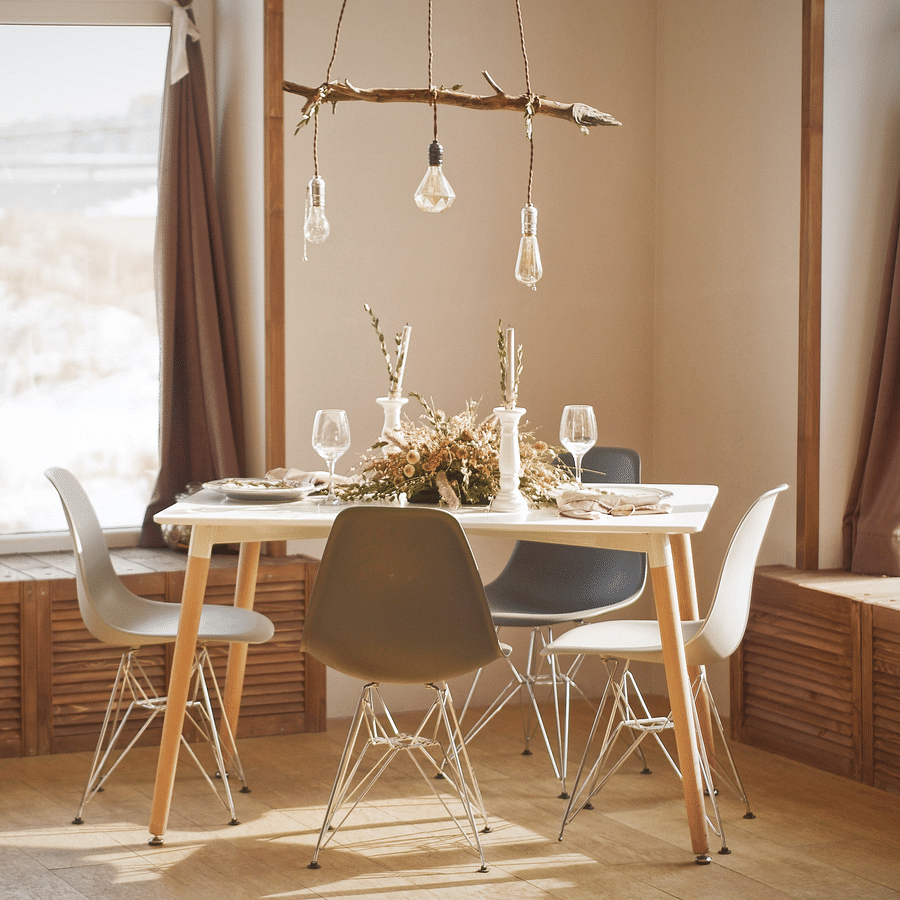 A dining room with a table set for a meal, chairs, and large windows.