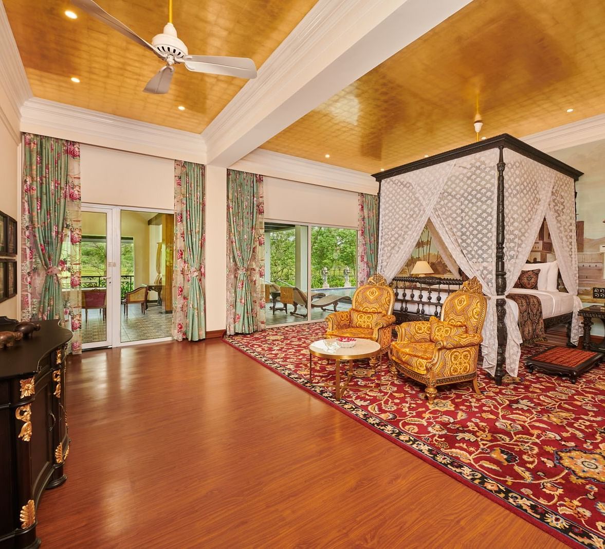 Four poster bed in a spacious suite with vintage decor and carpeted flooring.