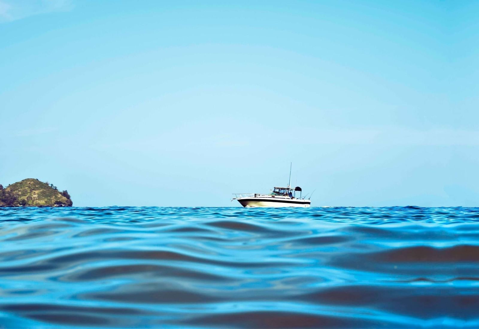A wide angle shot of a cruise boat sailing in the sea featuring a clear blue sky in the background.
