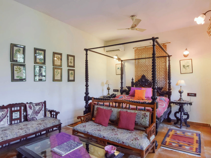An overview of the Vintage Room at Shaheen Bagh with a four poster bed, side tables, sofas, a coffee table and painting hung on the wal.