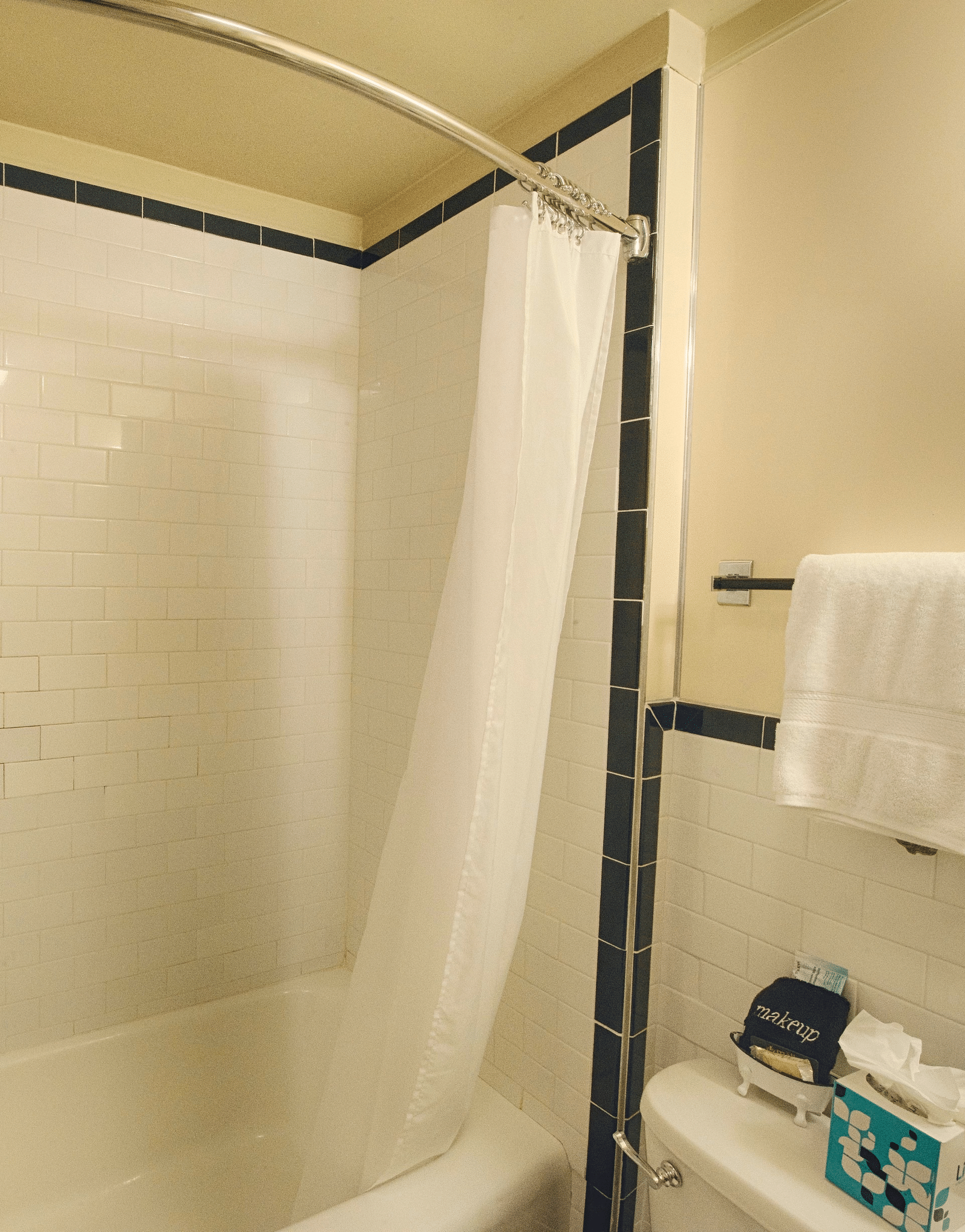 a bathtub with the shower curtains tucked inside the tub with a commode besides it - Historic Tapoco Lodge