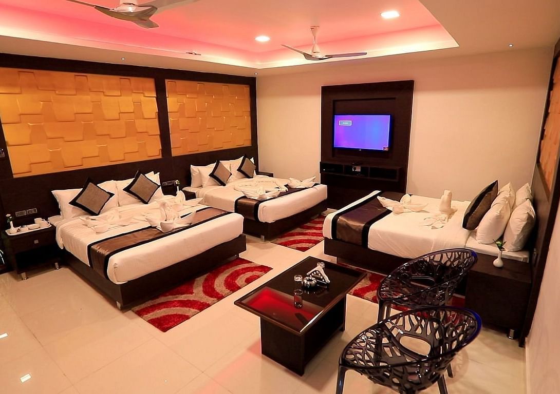 A room with three beds and a sitting area on the side at Parampara Residency, Kushalnagar.