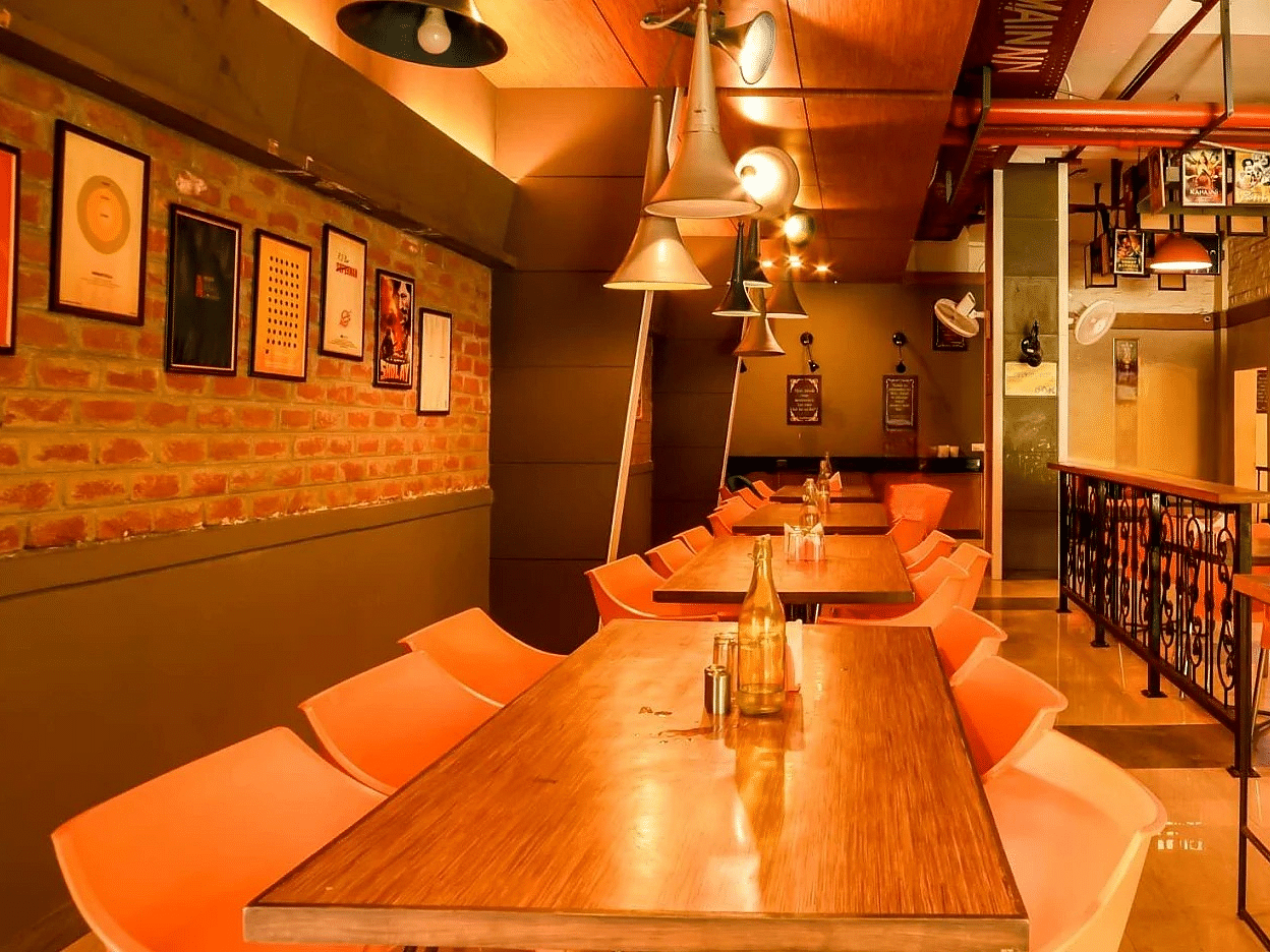 The interior of Mumbai Masala Restaurant, featuring chairs and wooden tables at Max Hotel Prayagraj.