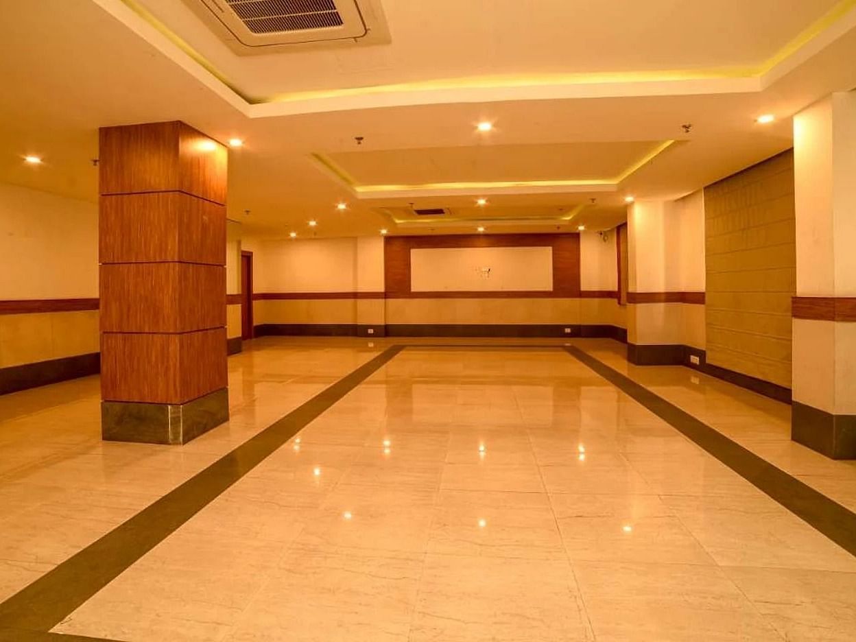 An interior of a banquet hall with tile flooring and warm lighting at Max Hotel Prayagraj.