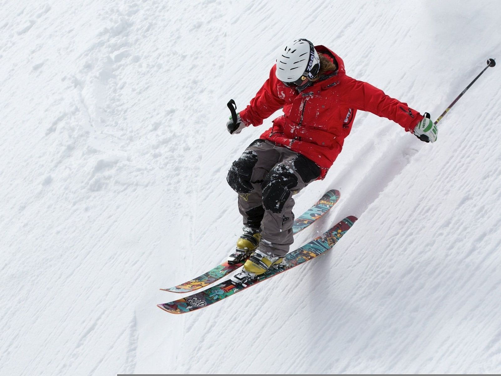 A close up shot of a person wearing a red jacket skiing on the slopes.