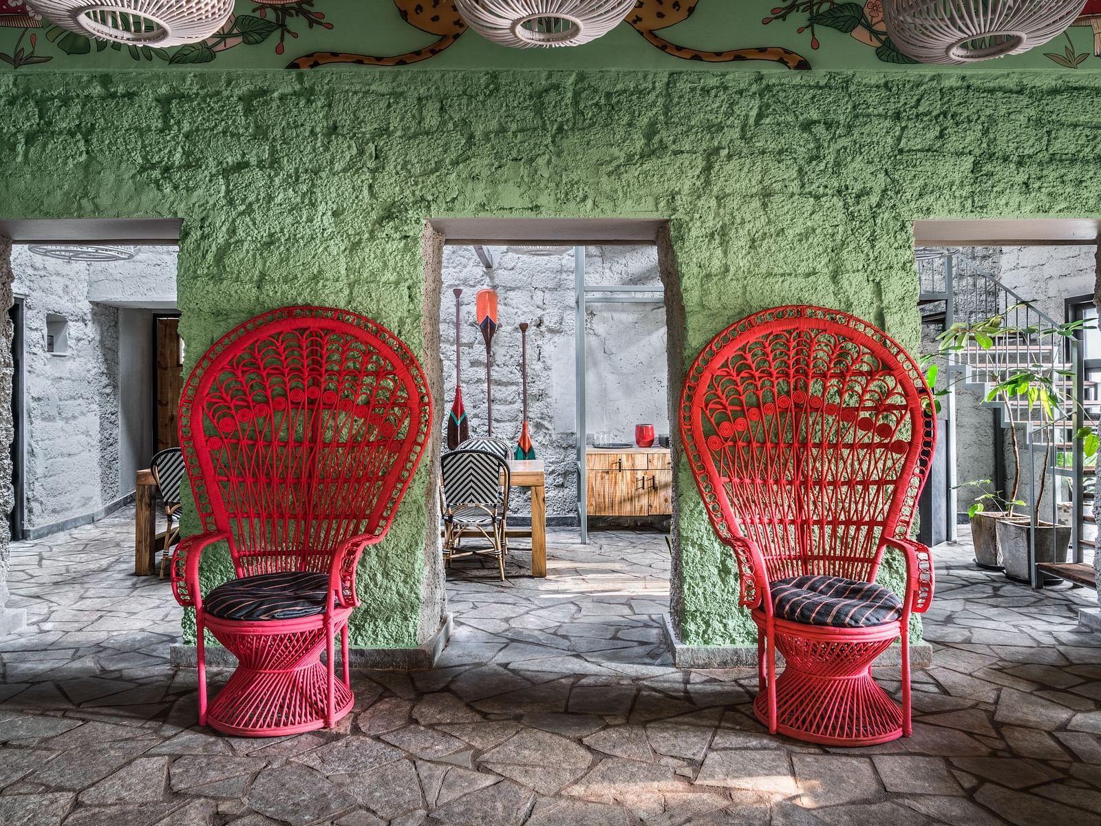 Two red single seaters in front of a green wall with access to a dining section next to it at Village 36