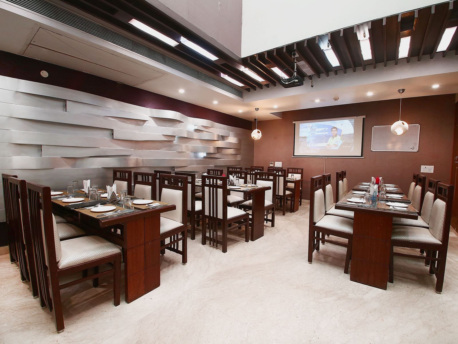 Modern dining space with various tables and chairs for guests to sit in and dine along with beautiful textured patterns on the wall and ambient  lighting - Hotel Emerald, Chandigarh