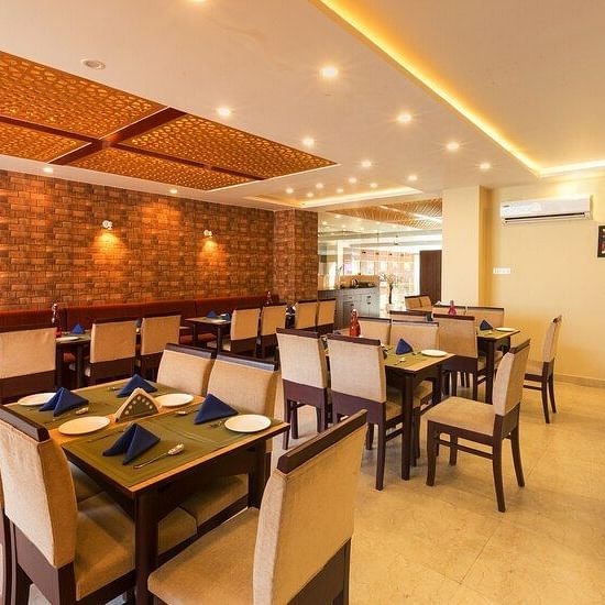 image of the indoor dining area with dining tables surrounded by off white cushioned chairs - ZENQ SIGNATURE INN, MCLEODGANJ