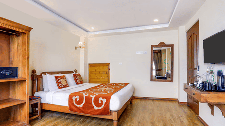 Two Bedroom Suite at Summit Hermon Hotel & Spa, Darjeeling with double bed, wooden cabinet, wall mirror, and mounted television screen.