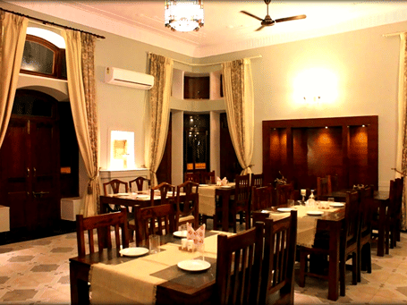Hotel Devnadi, Haridwar | A dining space with chairs, tables, and a fan.