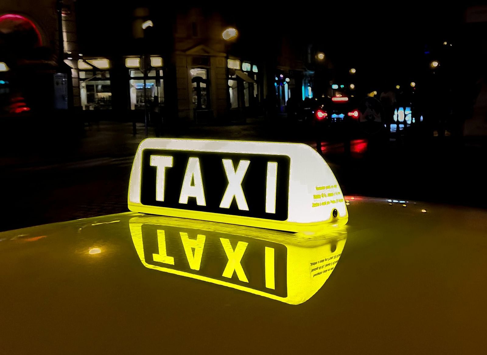 A yellow taxi sign illuminated at night.