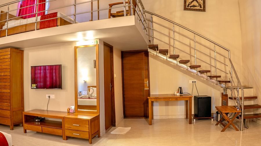 Attic Villa showcases a loft bedroom, a living area with a TV, and a staircase | Woodstock Resorts, Coorg