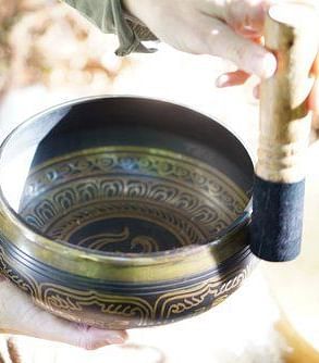 A detailed shot of a person performing sound healing using a Tibetan bowl - Brewery Gulch Inn & Spa