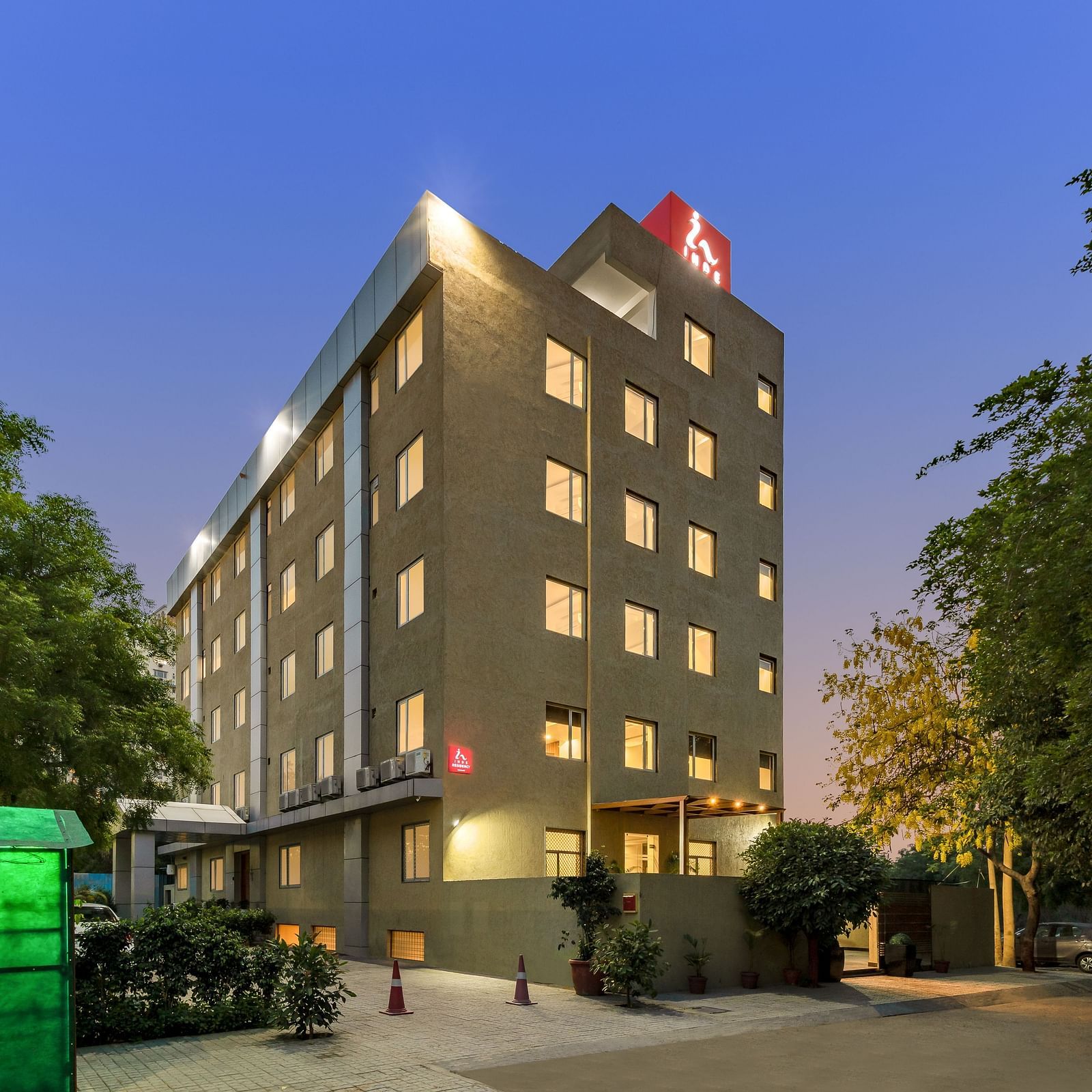 A facade image of a well-lit Inde Cyber City, Gurgaon building and beyond it an evening sky can be seen in the background - Inde Hotels & Resorts
