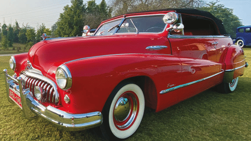 A poster for karma konnect with a red antique car - Karma Lakelands.